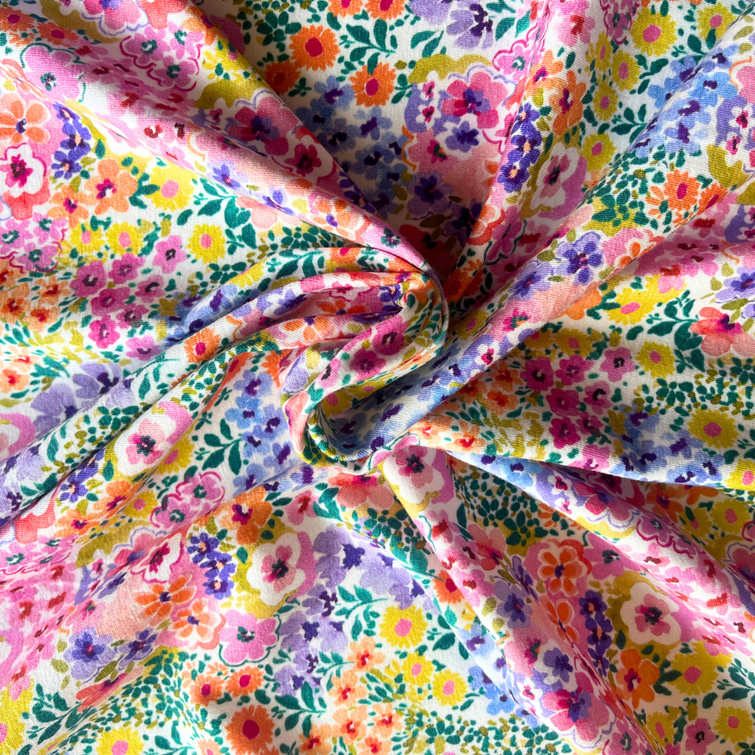 Flat lay of multicolour digital floral stretch jersey draped to show 200gsm weight and stretch — vibrant ditsy garden print fabric perfect for handmade jersey dresses and wrap styles