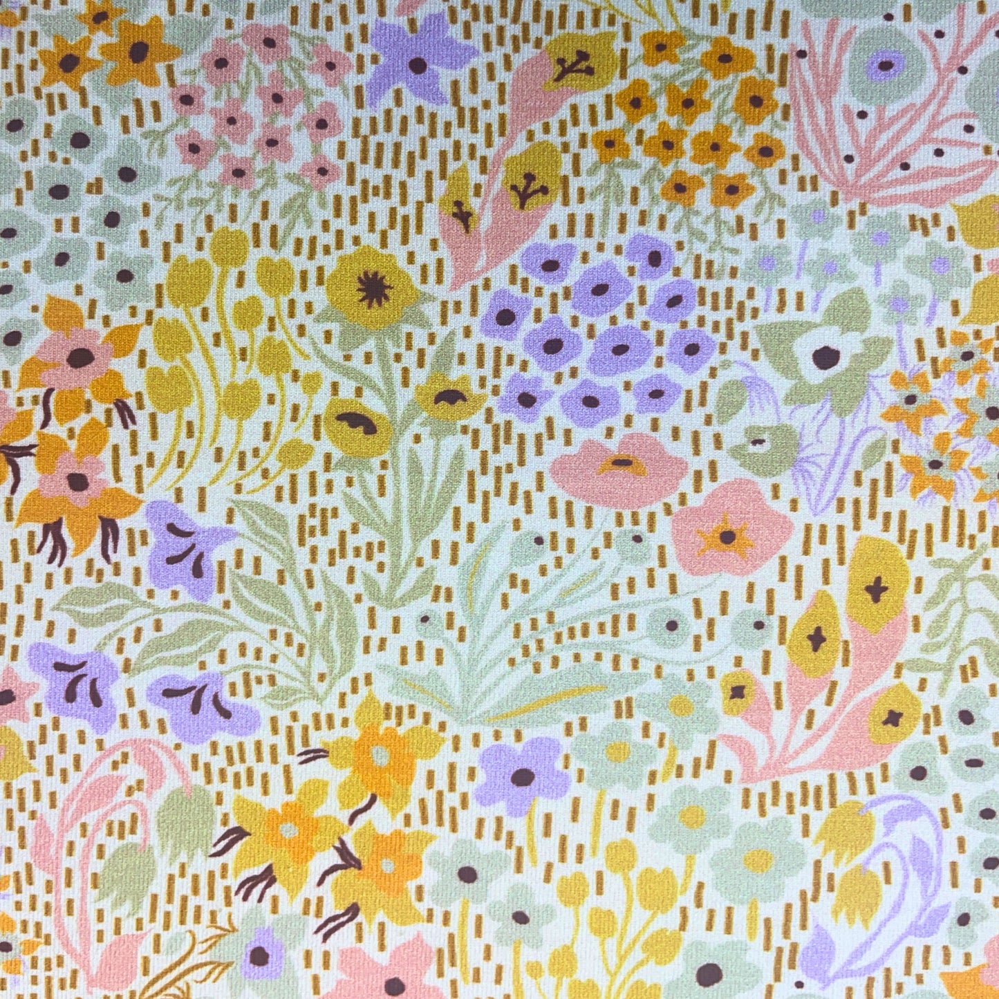 Pastel wildflower cotton jersey fabric draped to show its soft stretch and flow – beautiful for sewing t-shirts, leggings, or dresses