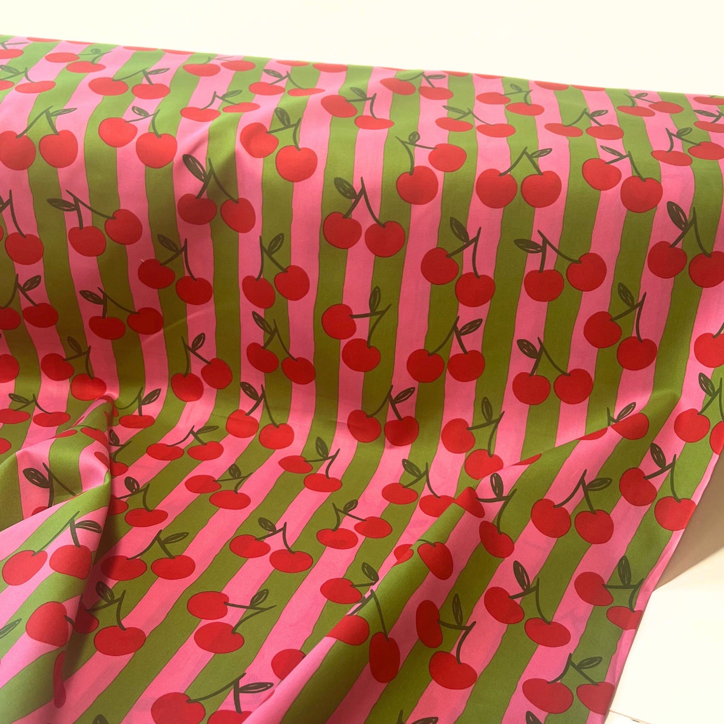 Breathable 100% cotton fabric with cherry motif and colourful stripes, shown styled for children’s clothing and joyful sewing projects.