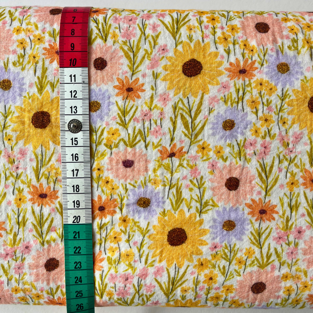 Sunflower meadow print double gauze in cheerful yellow, folded to reveal soft two-layer cotton construction — a beautiful spring and summer fabric for handmade dresses, skirts and rompers
