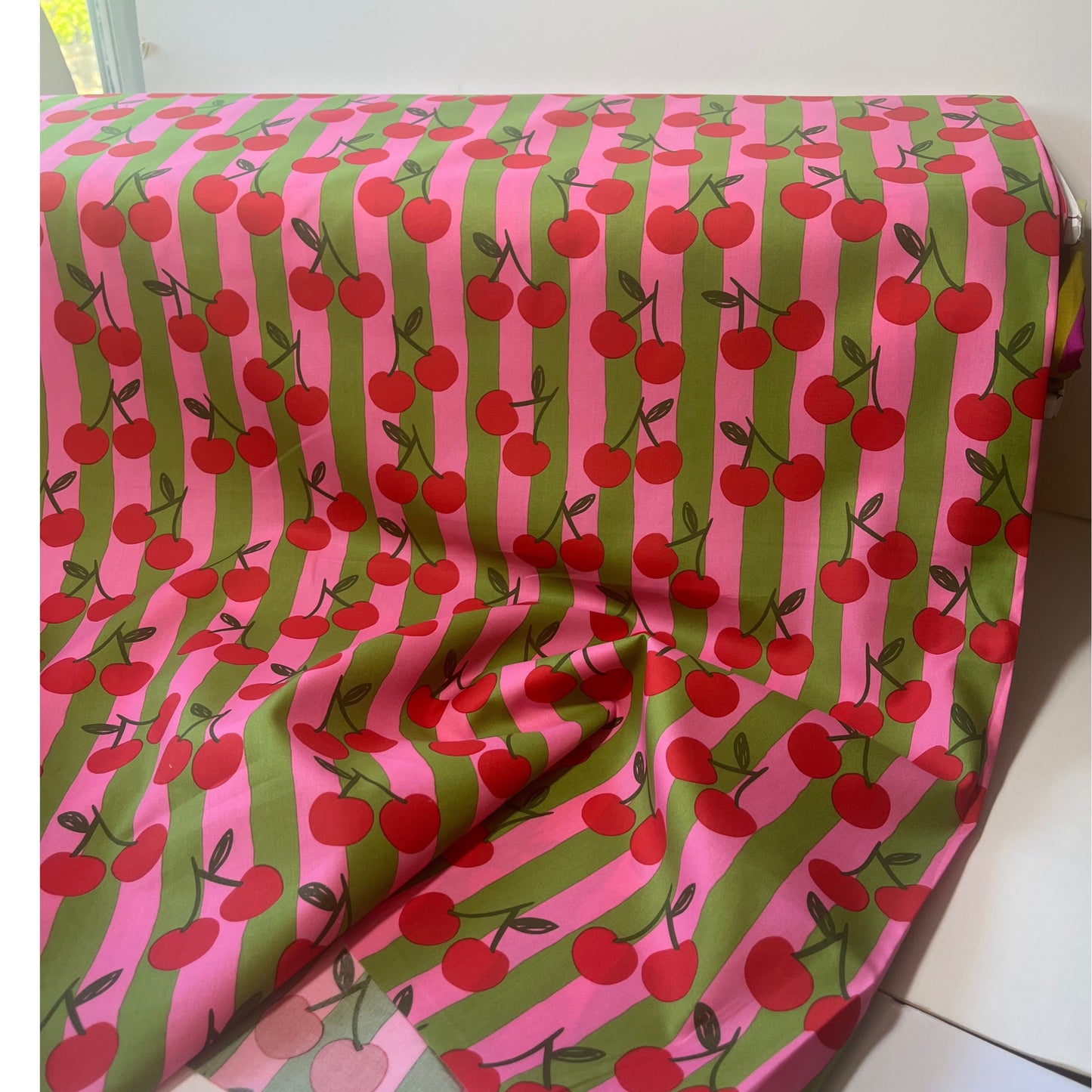 Breathable 100% cotton fabric with cherry motif and colourful stripes, shown styled for children’s clothing and joyful sewing projects.