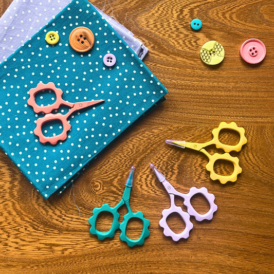 Close-up of sunflower-shaped embroidery scissors in bright coral, perfect for precision snipping and hand sewing