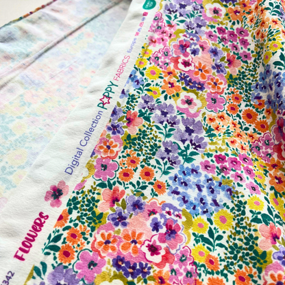 Flat lay of multicolour digital floral stretch jersey draped to show 200gsm weight and stretch — vibrant ditsy garden print fabric perfect for handmade jersey dresses and wrap styles