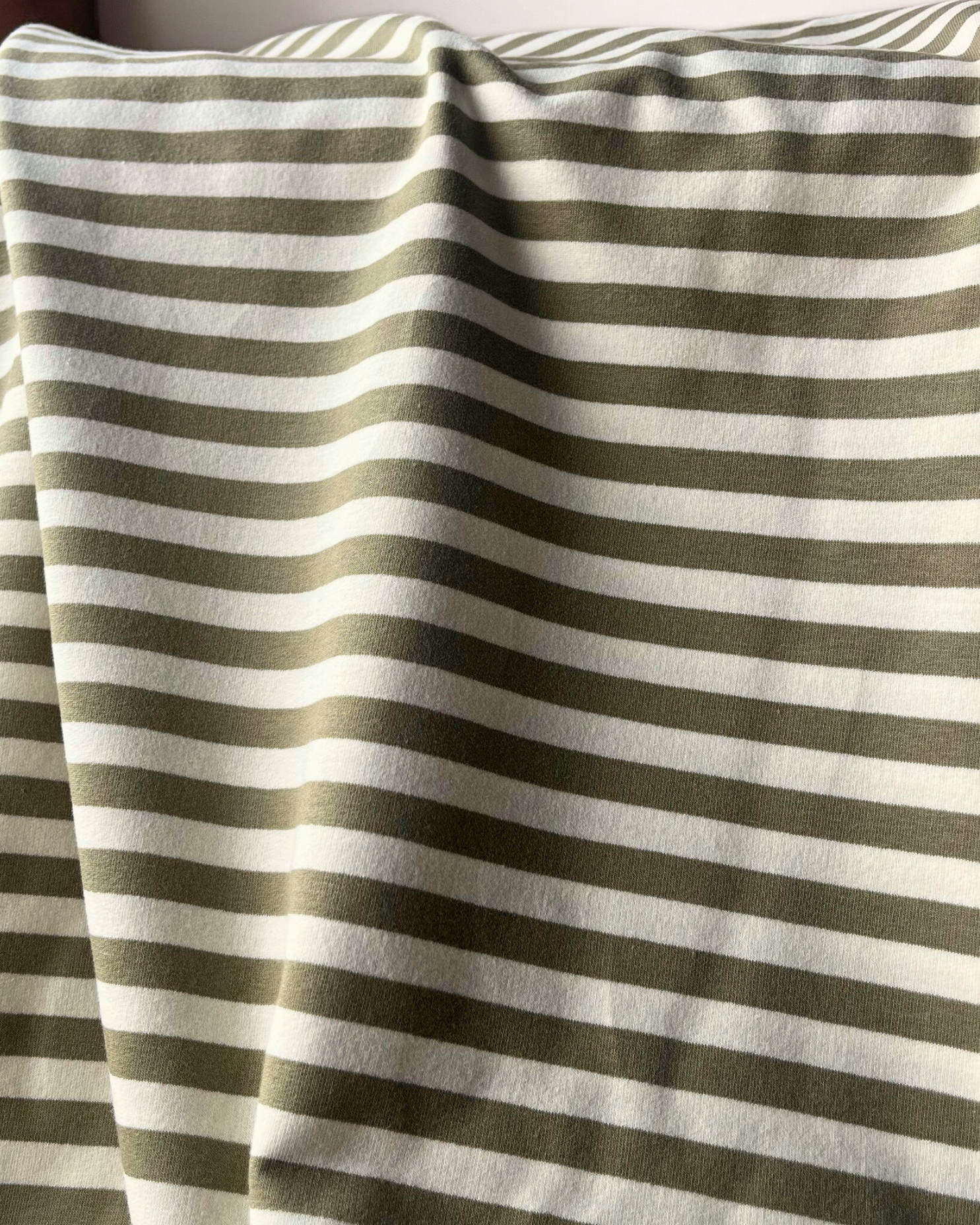 striped French terry fabric in sage green and warm white, draped to show 230gsm weight and stretch — ideal for handmade sweatshirts, joggers and co-ord sets