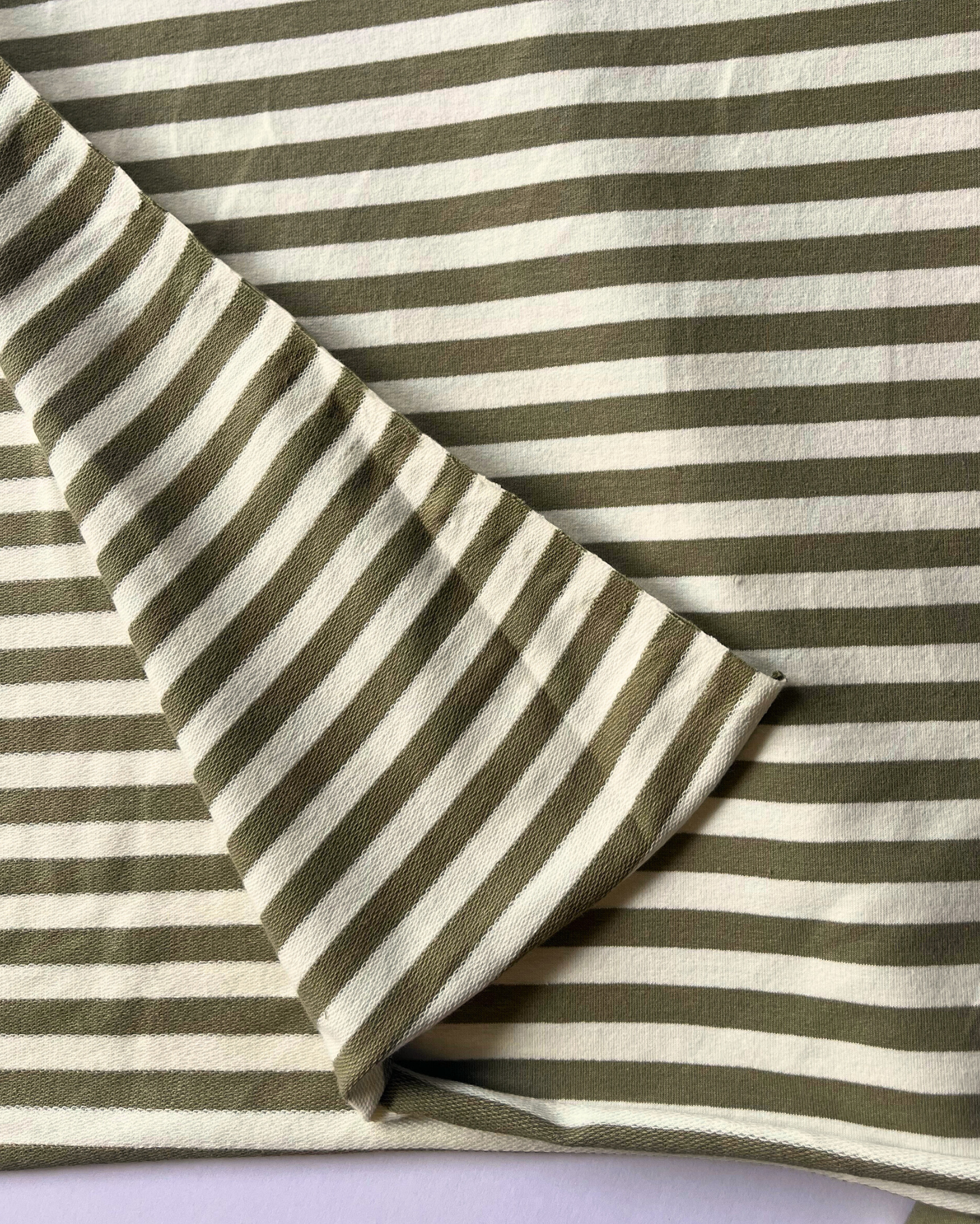 Narrow equal stripe yarn dyed French terry in earthy moss green and white, 95% cotton 5% elastane — slow fashion sweatshirting fabric for beginners and experienced sewists