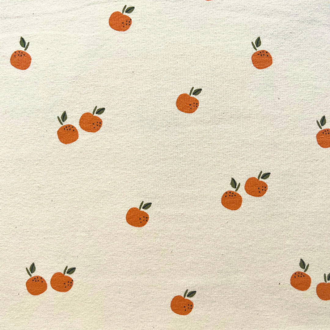 GOTS certified organic stretch jersey fabric in cream with small scattered oranges and fruits print, 148cm wide — soft cotton elastane knit ideal for handmade baby, children's and adult T-shirts