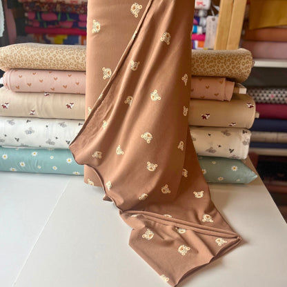 Leopard print cotton jersey fabric with cute illustrated leopard heads on brown background