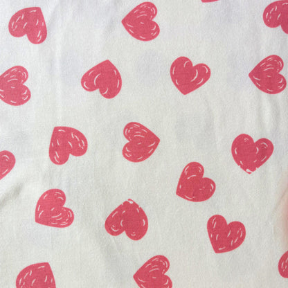Doodle hearts stretch jersey fabric in cream with scattered rose pink hand-drawn heart print, 150cm wide — 200gsm 95% cotton 5% elastane knit for handmade baby and children's clothing and loungewear