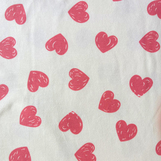 Doodle hearts stretch jersey fabric in cream with scattered rose pink hand-drawn heart print, 150cm wide — 200gsm 95% cotton 5% elastane knit for handmade baby and children's clothing and loungewear