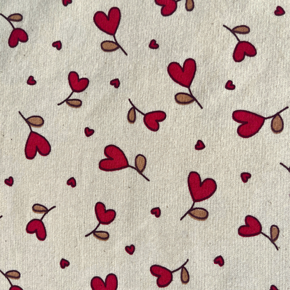 Close-up of supersoft brushed sweatshirting in natural and red, showing small scattered heart print on smooth fabric face and fluffy brushed reverse