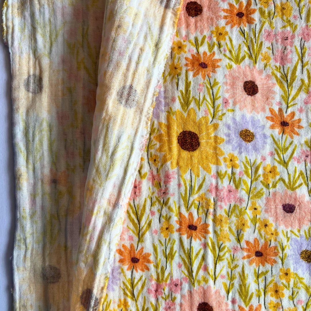 Close-up of yellow double gauze fabric showing digital sunflower print and soft two-layer woven texture — Oeko-Tex certified 100% cotton, ideal for babywear and adult dressmaking