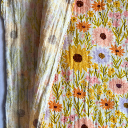 Close-up of yellow double gauze fabric showing digital sunflower print and soft two-layer woven texture — Oeko-Tex certified 100% cotton, ideal for babywear and adult dressmaking