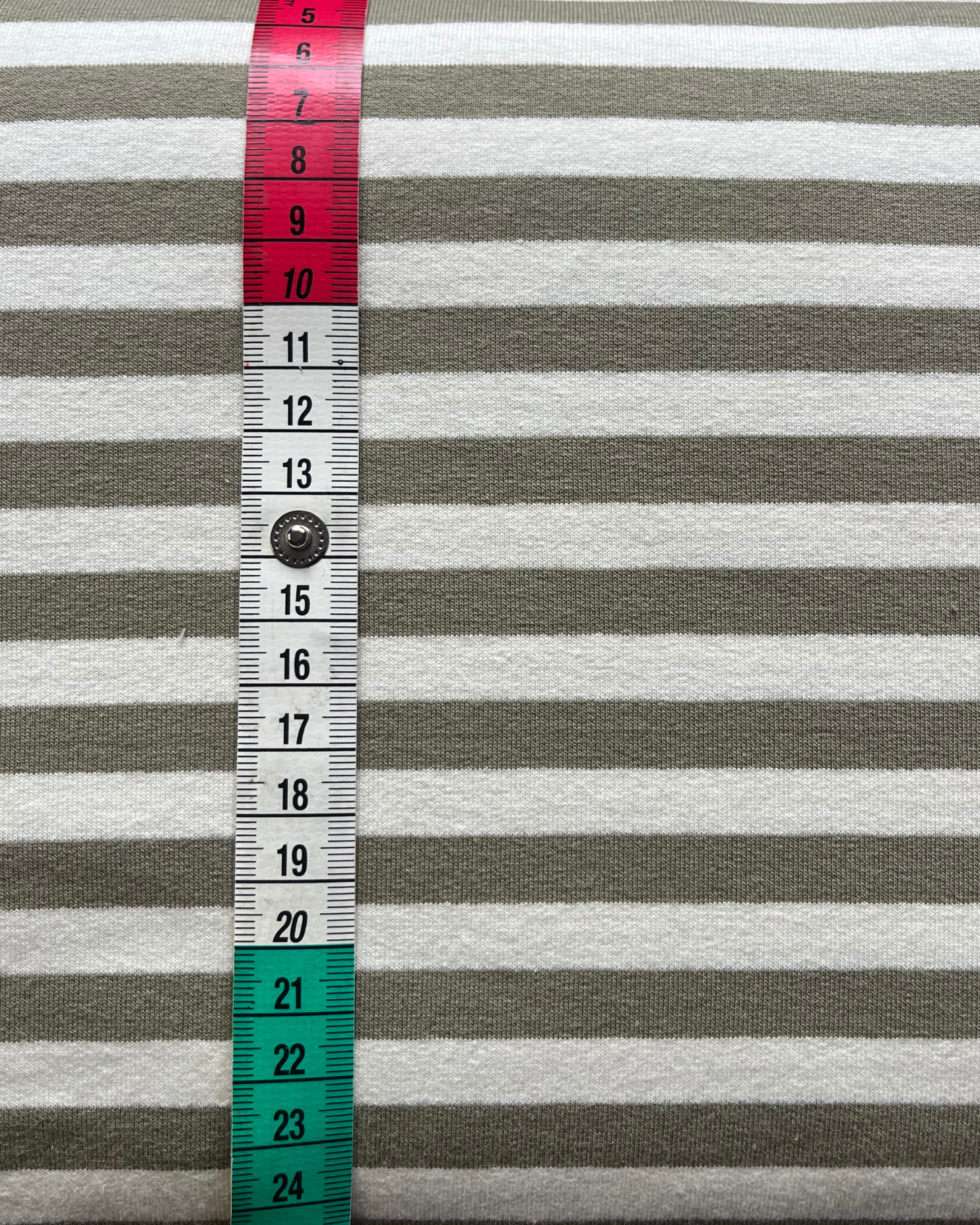 Close-up of moss green and warm white yarn dyed stripe French terry, showing clean stripe definition on smooth face and soft looped reverse visible at fold