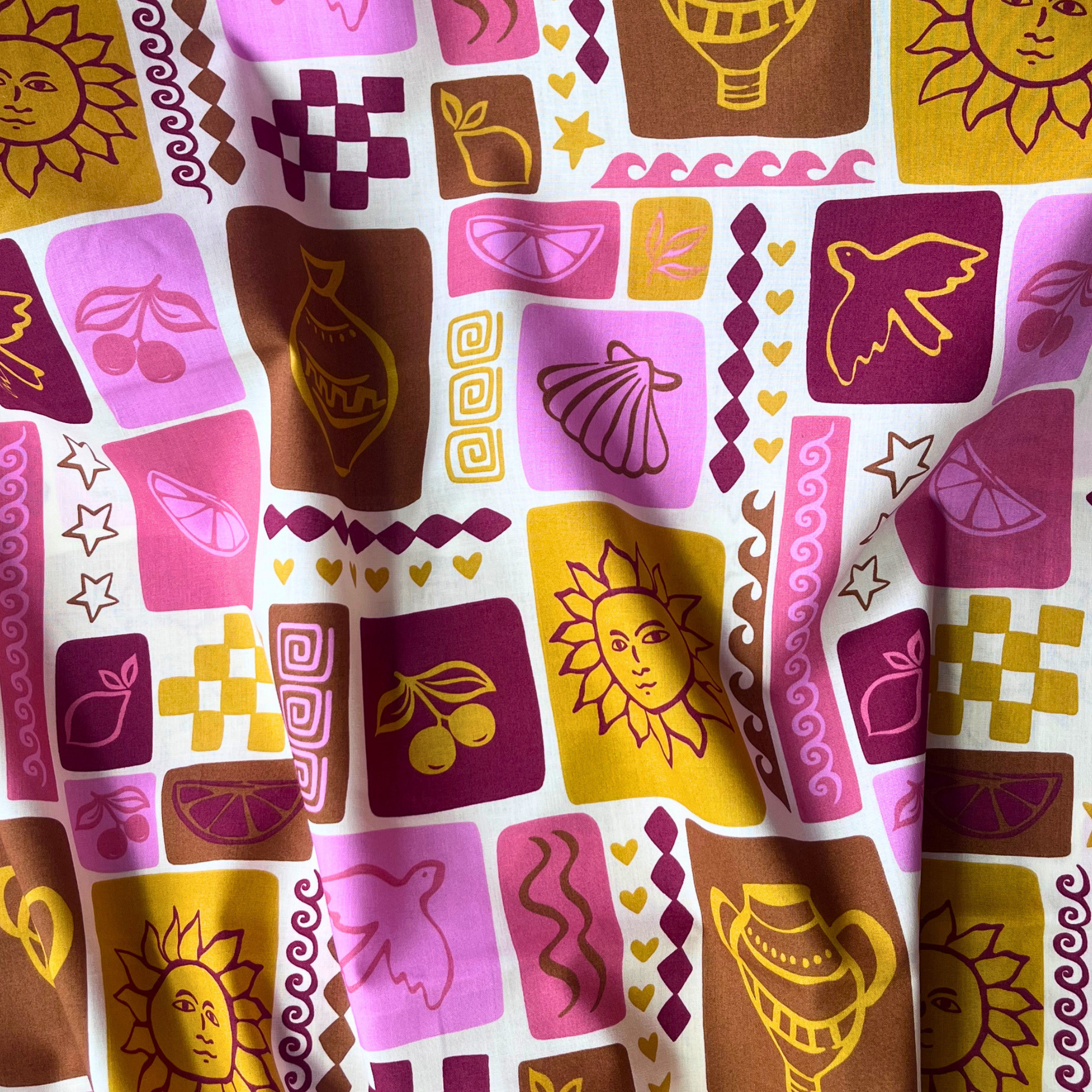 Close-up of off white cotton poplin showing patchwork style summer print with sketchy line drawn shells, bold suns, birds and fruit motifs in warm pink, red, mustard and ochre tones — Oeko-Tex Standard 100 certified, ideal for slow fashion summer dressmaking