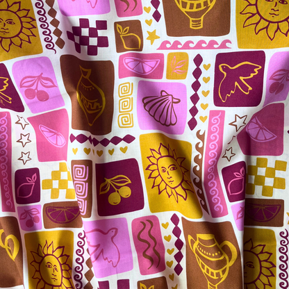 Close-up of off white cotton poplin showing patchwork style summer print with sketchy line drawn shells, bold suns, birds and fruit motifs in warm pink, red, mustard and ochre tones — Oeko-Tex Standard 100 certified, ideal for slow fashion summer dressmaking