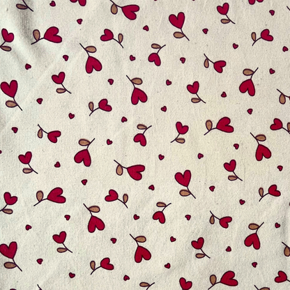Close-up of supersoft brushed sweatshirting in natural and red, showing small scattered heart print on smooth fabric face and fluffy brushed reverse