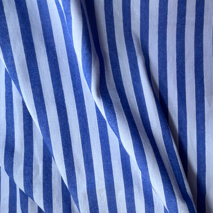 A close-up of draped fabric with vertical blue and white stripes, showing soft folds and texture.
