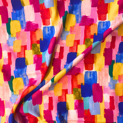 Close-up of colourful viscose rayon fabric showing large scale digitally printed abstract brushstroke design in vivid pink, orange, yellow, blue and green — soft fluid 100% viscose from Little Johnny ideal for slow fashion dressmaking and statement garments