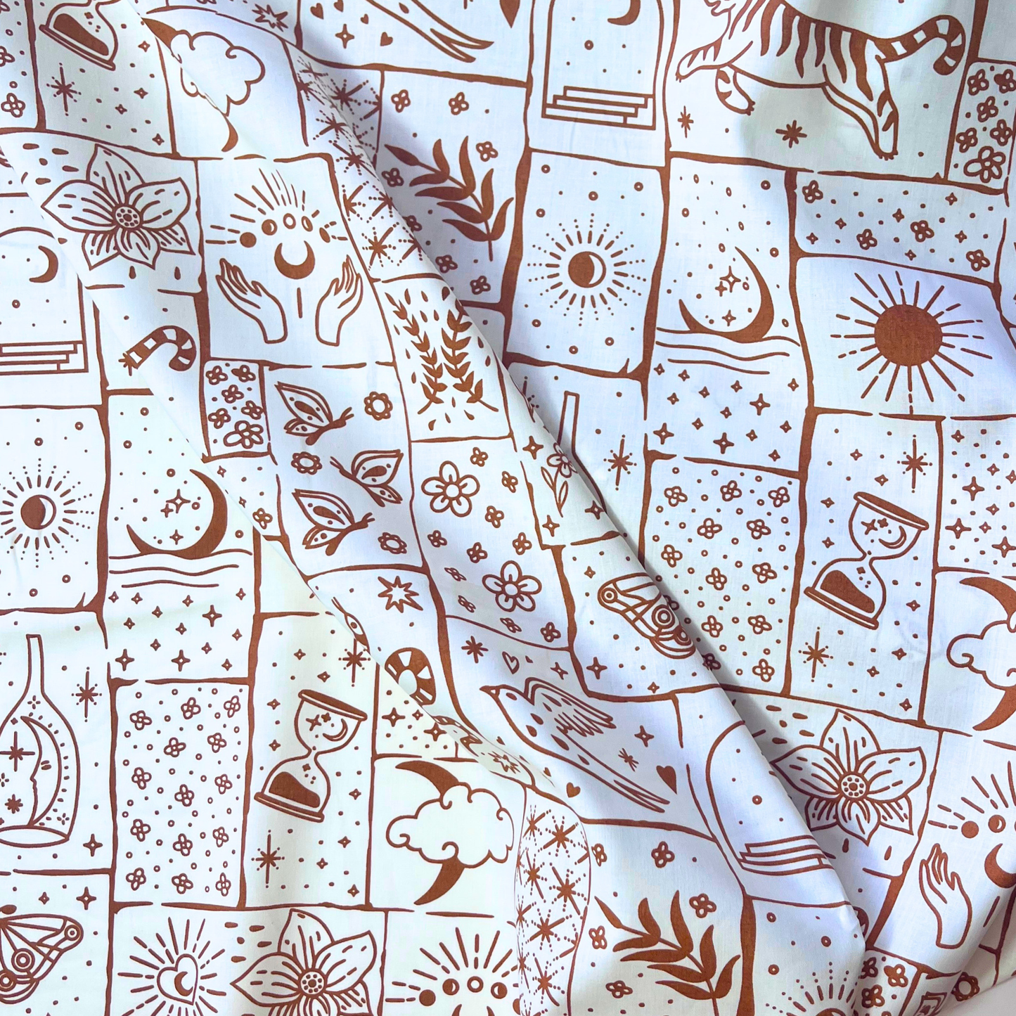 Celestial patchwork print cotton poplin fabric on white base with irregular caramel and ginger patches filled with tigers, florals, stars and moons, 148cm wide — lightweight 110gsm 100% cotton woven for handmade statement blouses, dresses and wide-leg trousers