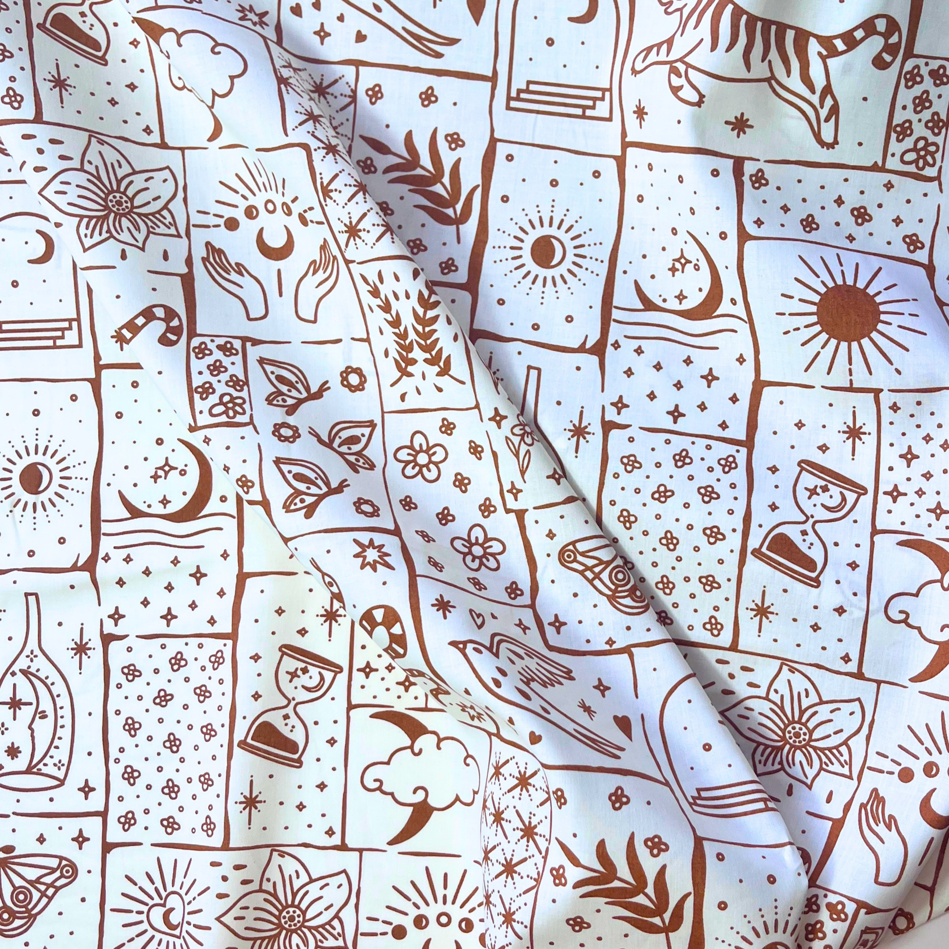 Celestial patchwork print cotton poplin fabric on white base with irregular caramel and ginger patches filled with tigers, florals, stars and moons, 148cm wide — lightweight 110gsm 100% cotton woven for handmade statement blouses, dresses and wide-leg trousers