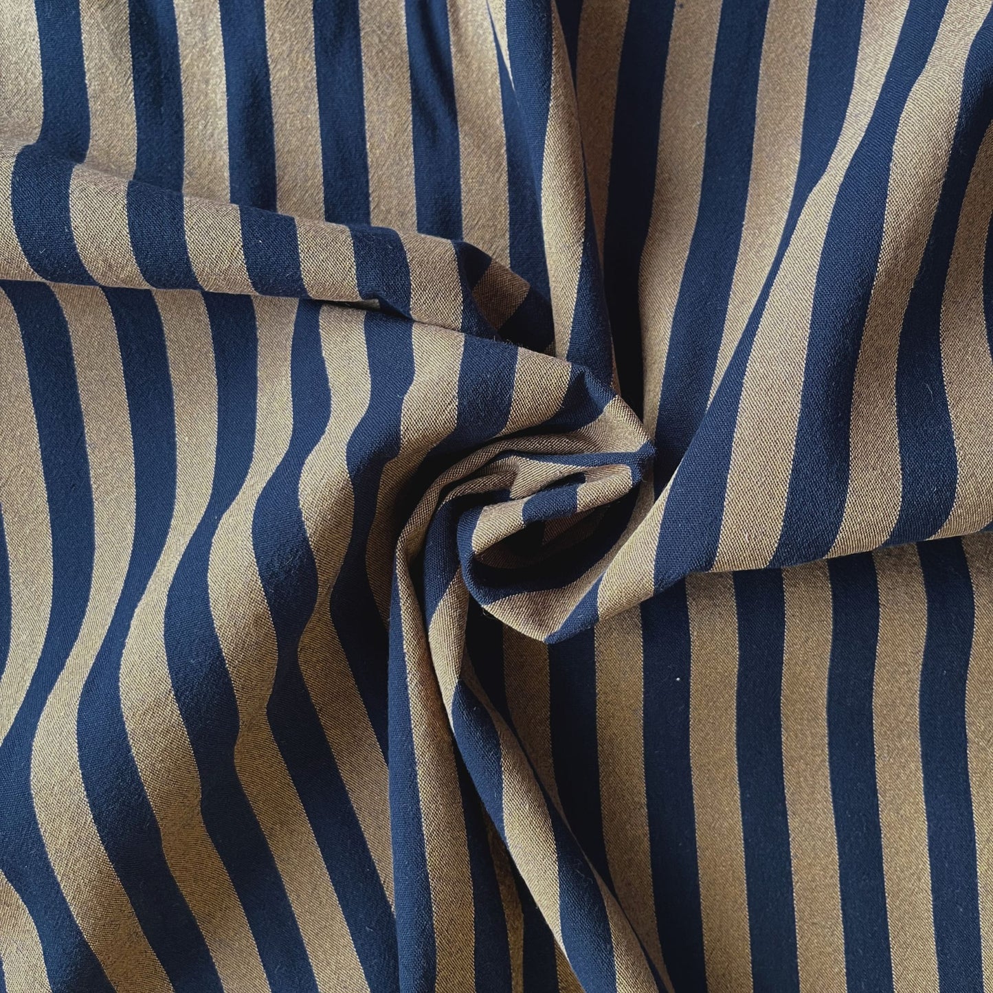 Flat lay of navy and brown yarn dyed stripe fabric draped to show lightweight 115gsm drape and generous 145cm width — classic cotton stripe woven fabric perfect for handmade shirts and summer dresses
