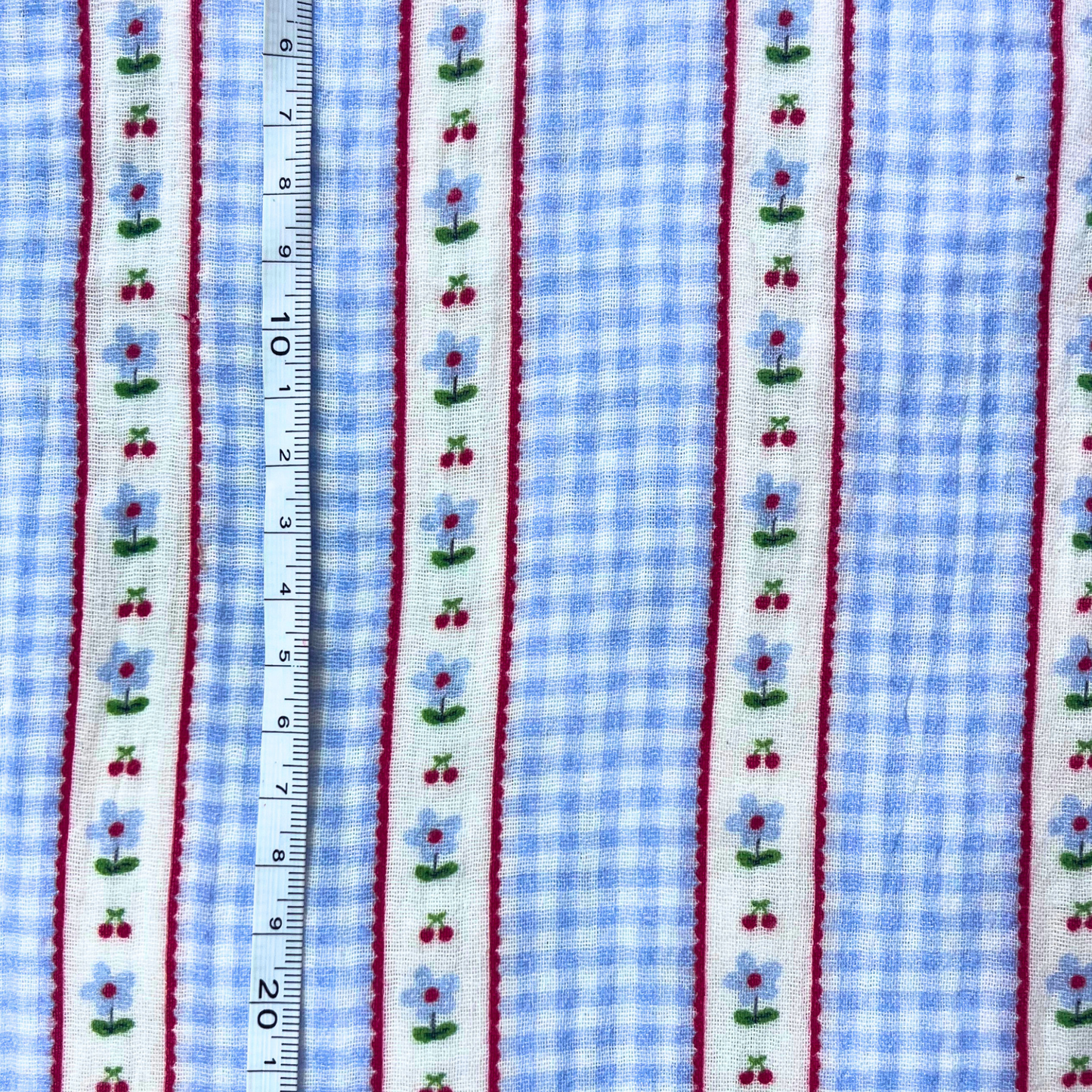 Flat lay of Poppy Fabrics double gauze digital check in light blue and white draped to show featherlight 125gsm weight and soft two-layer construction — gingham check with subtle vertical stripe detail perfect for handmade summer dresses and playsuits