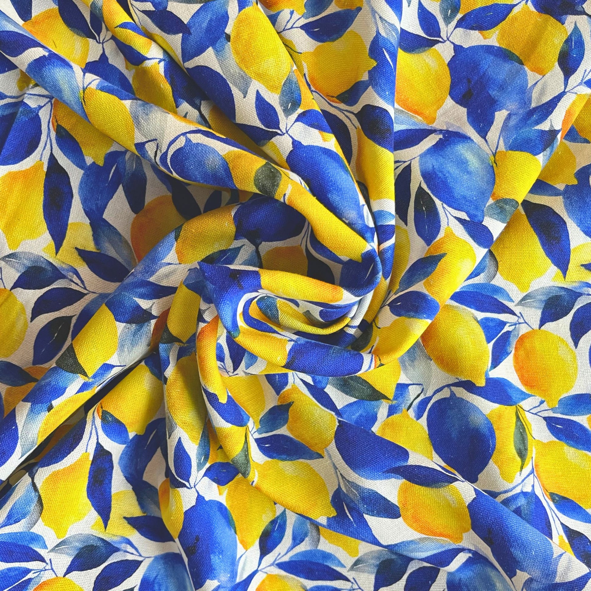Flat lay of white lemon print linen mix fabric draped to show natural texture and fluid drape — bold Mediterranean citrus print on 55% linen 45% viscose woven, perfect for handmade summer dresses and shirts