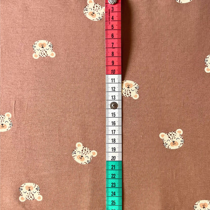 Close-up of playful leopard face print on warm earthy toned knit fabric.