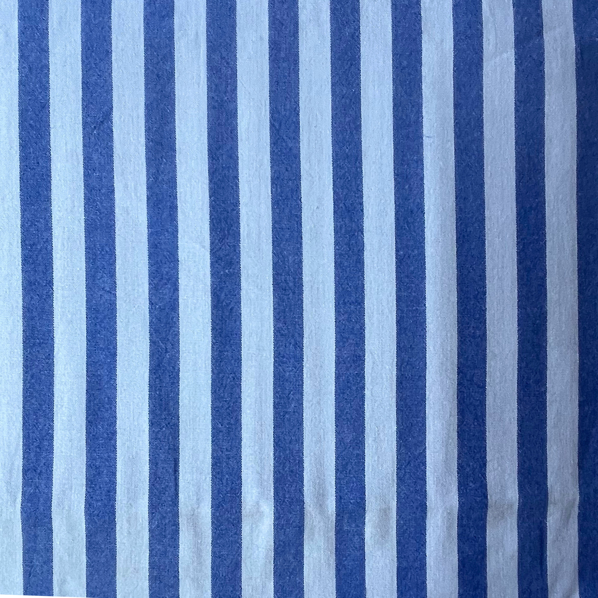 Blue and light blue vertically striped yarn dyed cotton dressmaking fabric with a visible woven texture.