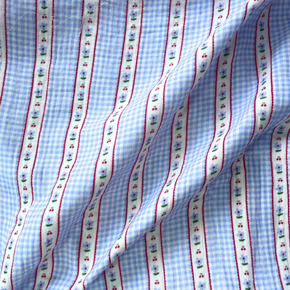 Close-up of light blue and white gingham double gauze fabric showing delicate vertical ditsy stripe running through classic check print — soft two-layer Oeko-Tex certified 100% cotton woven ideal for handmade baby muslins and children's dresses