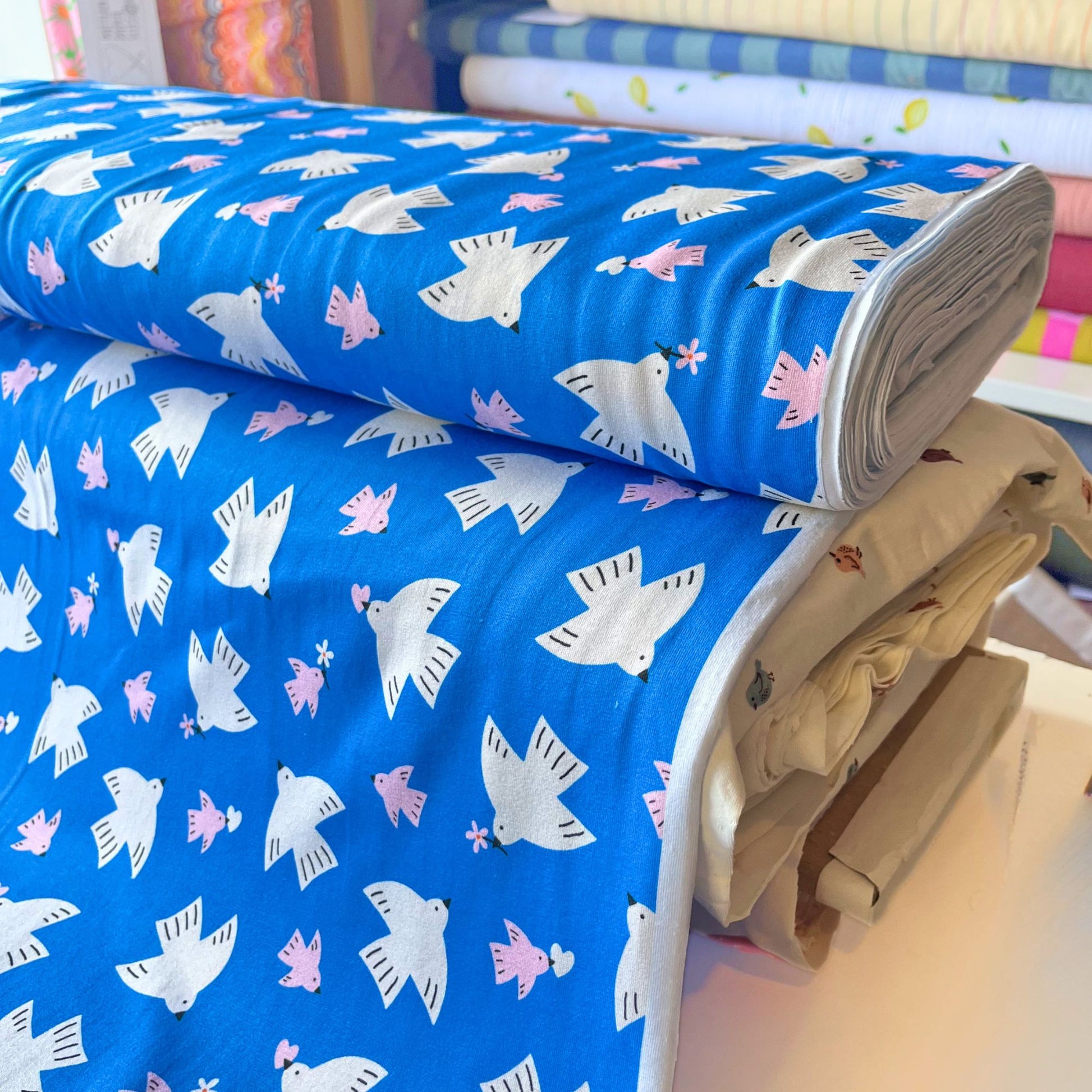 Bright blue digital print cotton jersey with white and pink bird motifs and floral details — soft breathable 100% cotton knit for handmade children's clothing, adult dresses and slow fashion makes