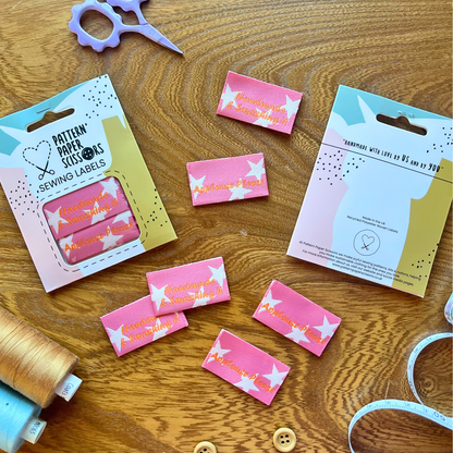 Pink and orange woven sewing label with white stars reading Handmade and Smashing It — folded sew-in style, soft and gentle on sensitive skin, perfect for handmade garments and gifts