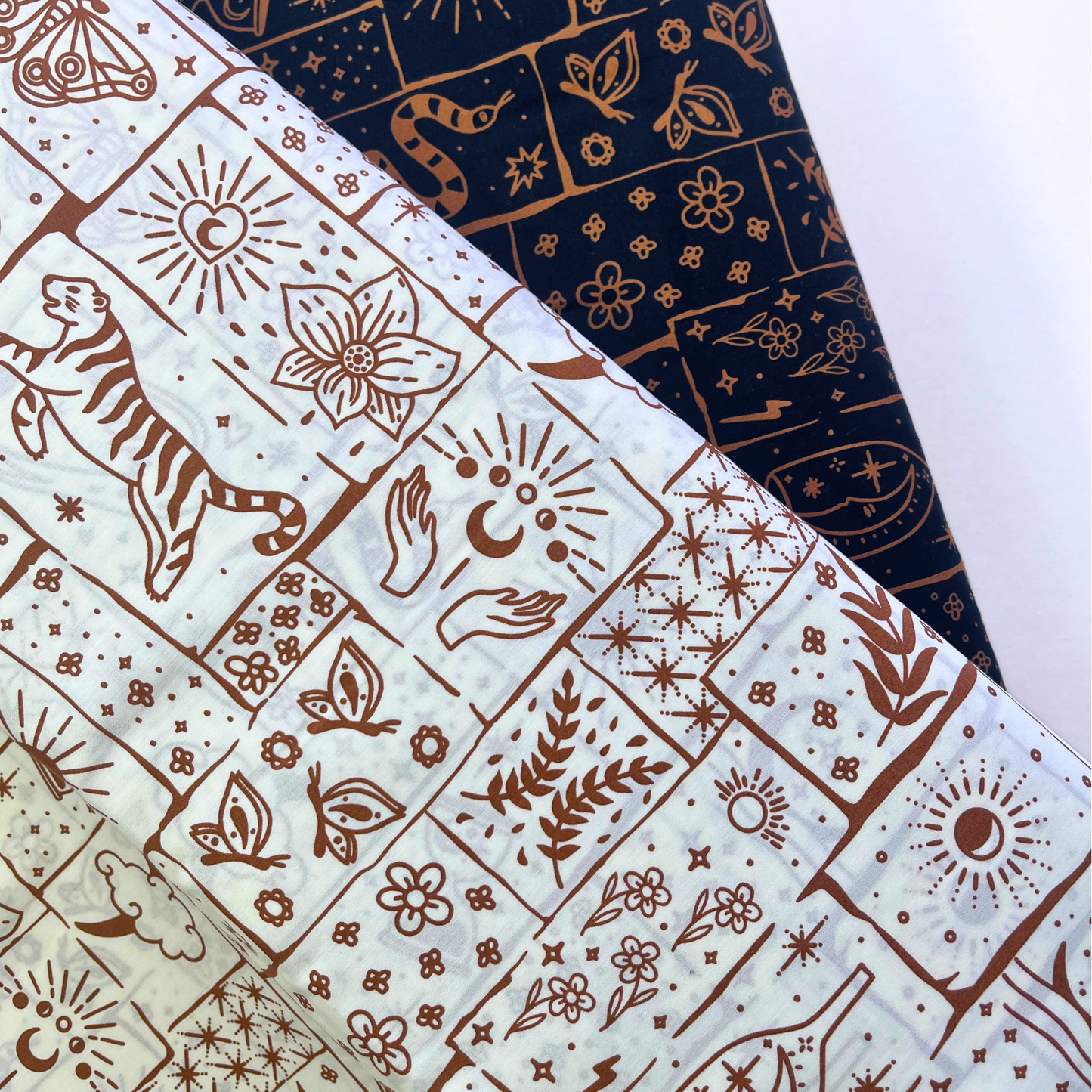 Black and white based celestial patchwork cotton poplin folded to show crisp woven construction and rich caramel and ginger tiger floral star print — lightweight breathable fabric ideal for handmade blouses, midi skirts and statement wide-leg trousers