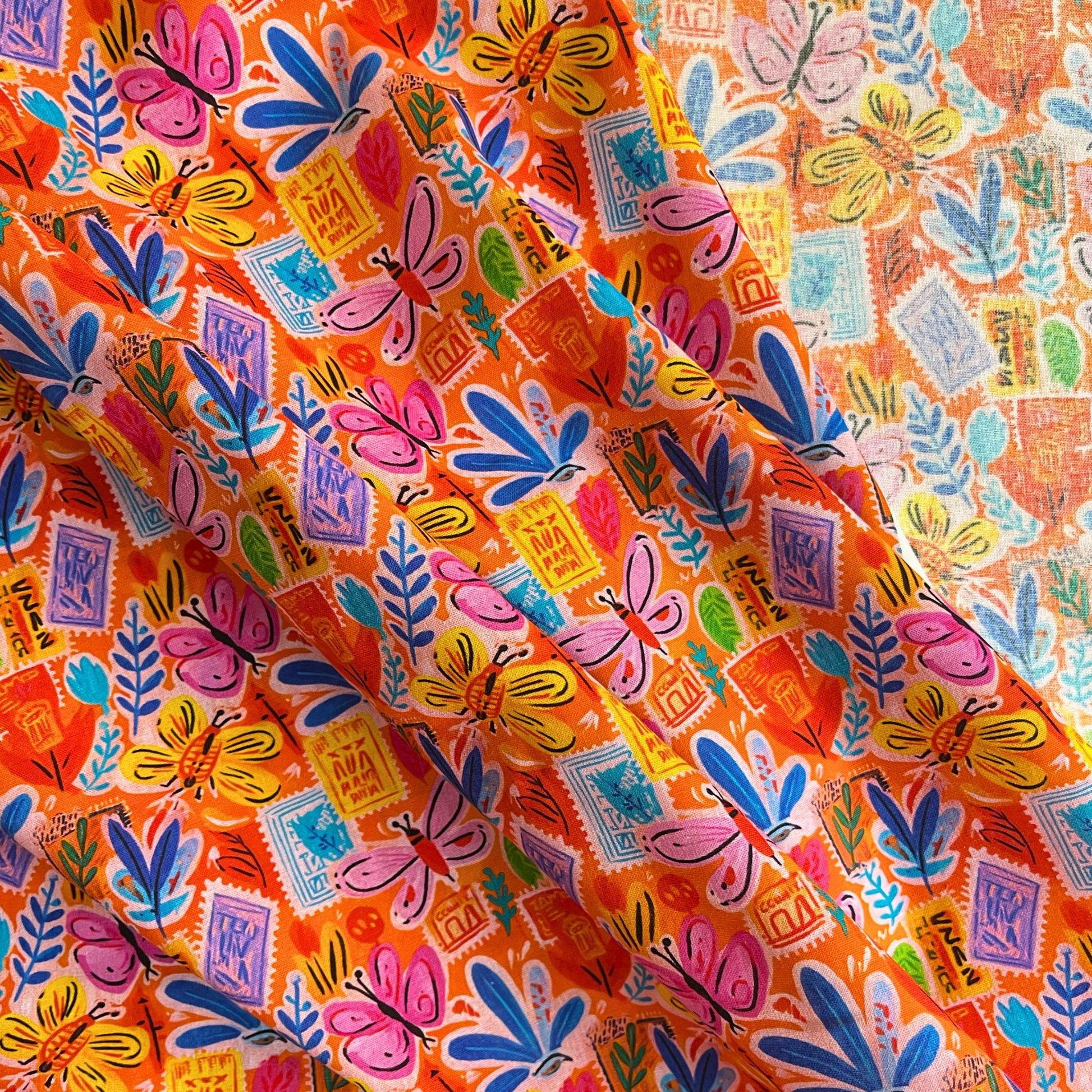 Vibrant orange cotton fabric with scattered postcard scenes, botanical florals and butterflies — Empee Studio 100% cotton woven fabric with vintage illustrated charm for slow fashion dressmaking and handmade children's clothing