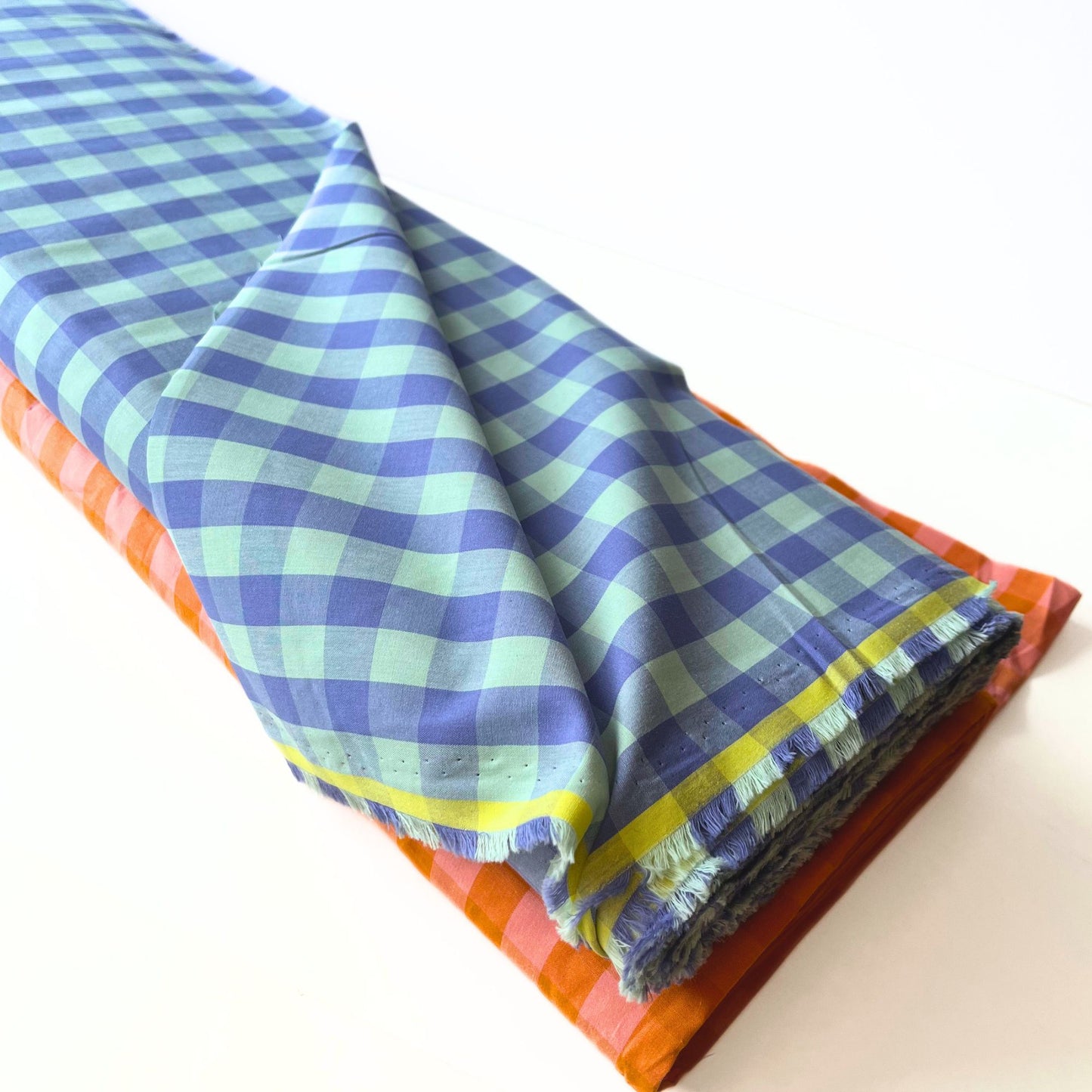 Flat lay of lavender and mint gingham check fabric draped to show lightweight 115gsm drape and generous 145cm width — yarn dyed cotton woven perfect for summer dresses and children's clothing