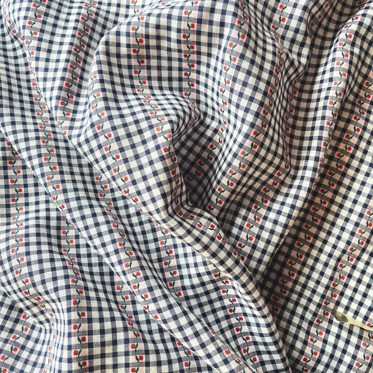 Flat lay of navy white and red jacquard gingham fabric draped to show fine 90gsm weight and elegant drape — intricate woven floral on mini gingham base, perfect for handmade blouses and tailored dresses