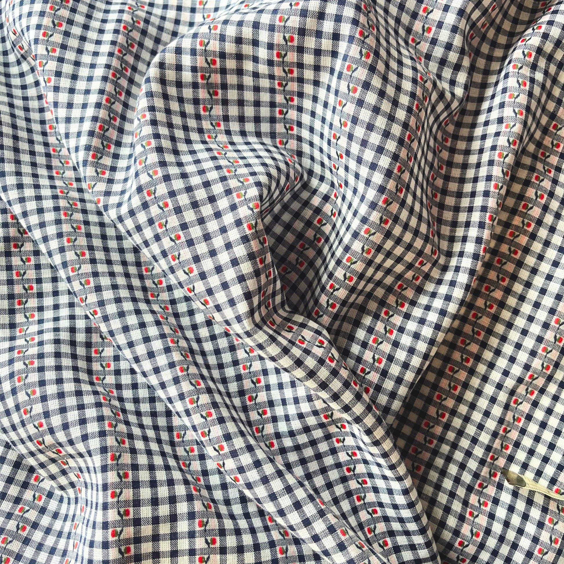 Flat lay of navy white and red jacquard gingham fabric draped to show fine 90gsm weight and elegant drape — intricate woven floral on mini gingham base, perfect for handmade blouses and tailored dresses