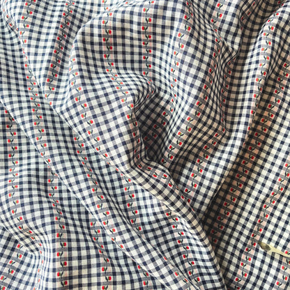 Flat lay of navy white and red jacquard gingham fabric draped to show fine 90gsm weight and elegant drape — intricate woven floral on mini gingham base, perfect for handmade blouses and tailored dresses
