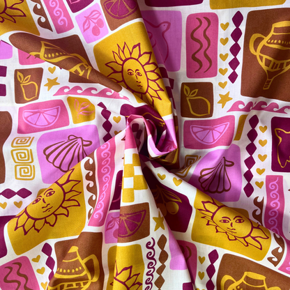 Summer patchwork print cotton poplin from Poppy Fabrics folded to show crisp woven construction and warm holiday inspired print of shells, suns, birds and fruit in pink, red, mustard and ginger tones — lightweight breathable fabric ideal for handmade blouses, midi skirts and summer dresses