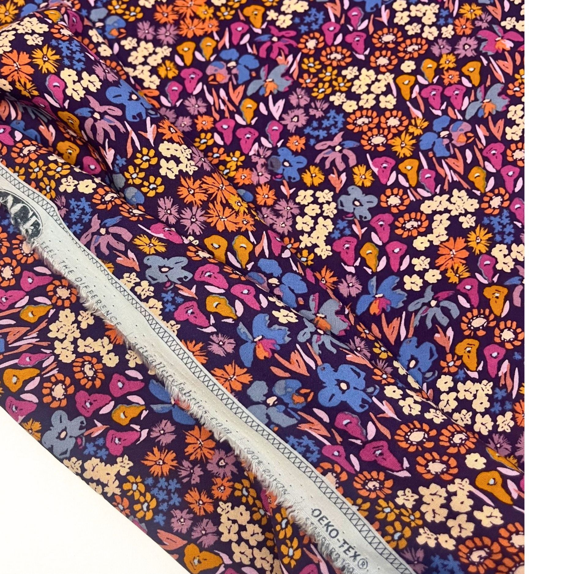 Close-up of Dusk Fusion rayon fabric by AGF Studio showing rich floral meadow print in sunset tones of copper, purple, and pink