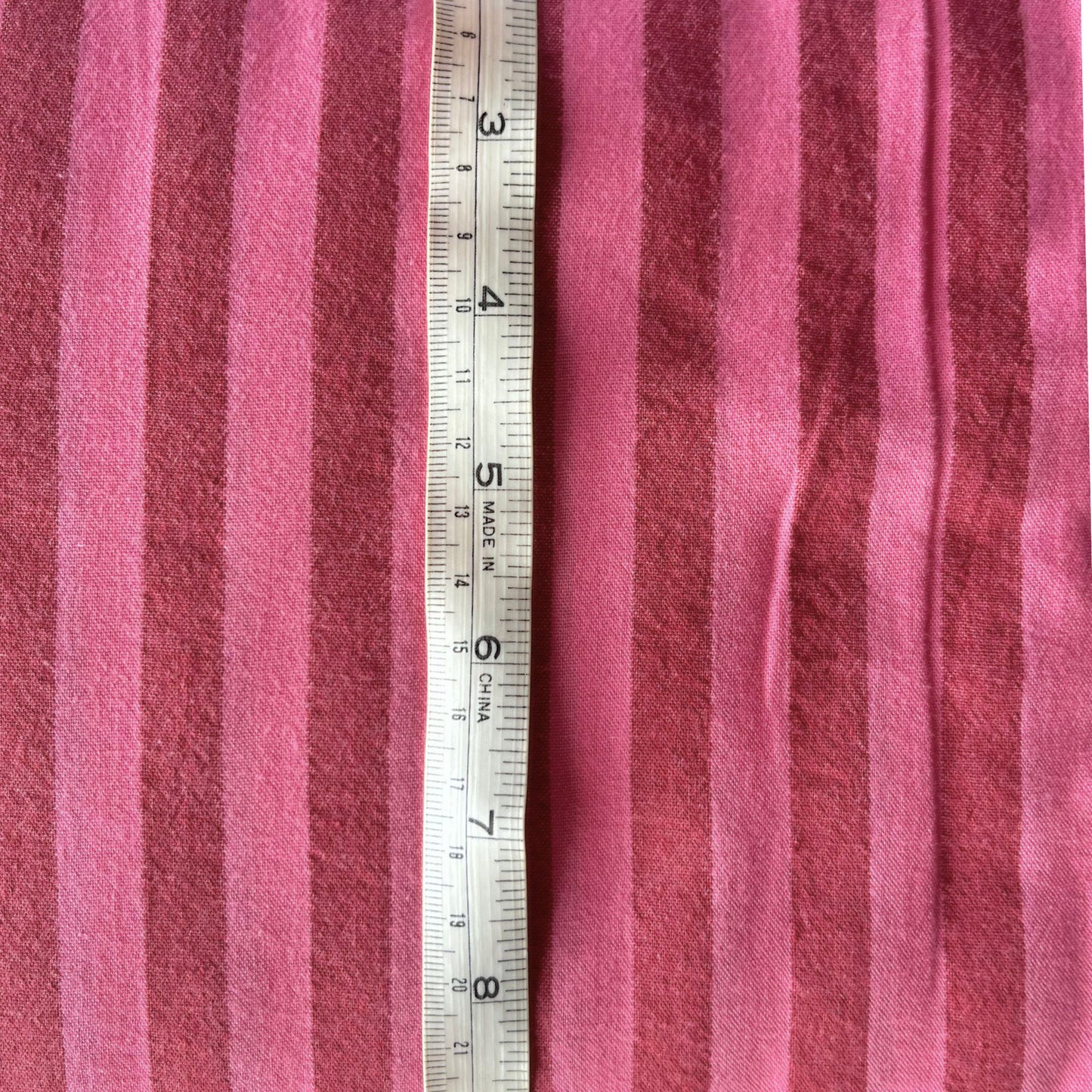 Washed pink and red cotton yarn dyed stripe fabric folded to show soft laundered colour definition — lightweight breathable woven fabric ideal for handmade blouses, skirts, wide-leg trousers and summer dresses