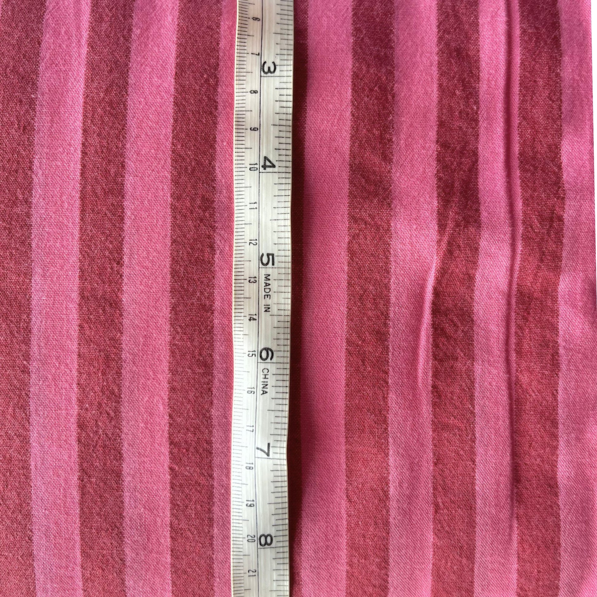 Washed pink and red cotton yarn dyed stripe fabric folded to show soft laundered colour definition — lightweight breathable woven fabric ideal for handmade blouses, skirts, wide-leg trousers and summer dresses