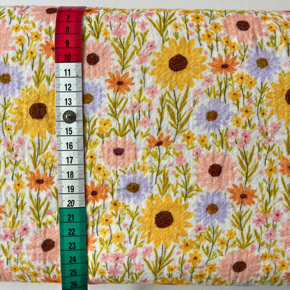 Sunflower meadow print double gauze in cheerful yellow, folded to reveal soft two-layer cotton construction — a beautiful spring and summer fabric for handmade dresses, skirts and rompers