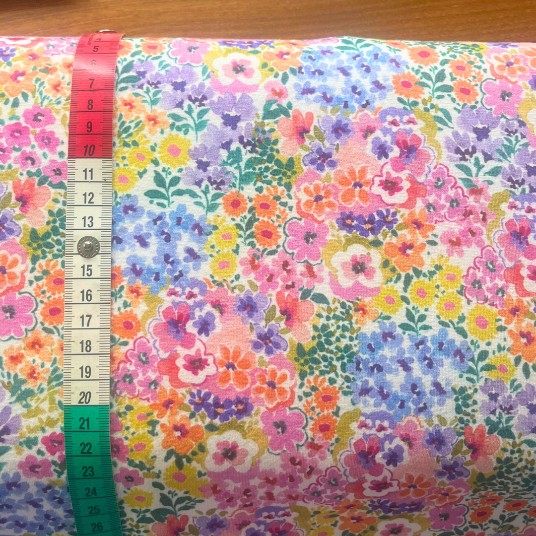 Multicolour ditsy digital flowers jersey fabric folded to show soft knit construction — a vibrant garden bloom print in Oeko-Tex certified cotton stretch, perfect for dresses, tops and skirts