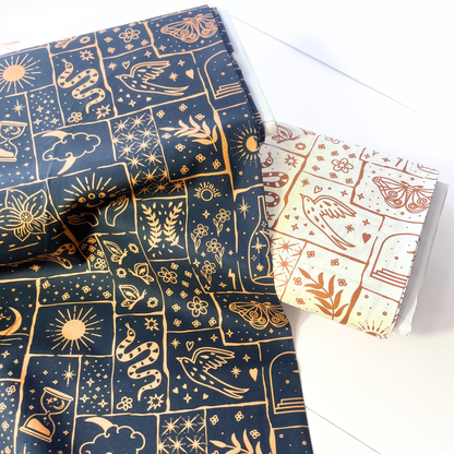 Flat lay of black base celestial patchwork poplin fabric draped to show crisp lightweight 110gsm drape — irregular caramel and ginger patches with tigers, florals and moons, perfect for handmade shirt dresses and statement co-ords
