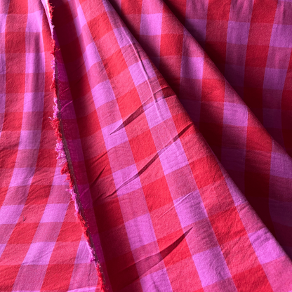 Close-up of bold red and cerise pink yarn dyed gingham showing crisp woven check lines and vibrant colour depth — Oeko-Tex Standard 100 certified cotton dressmaking fabric