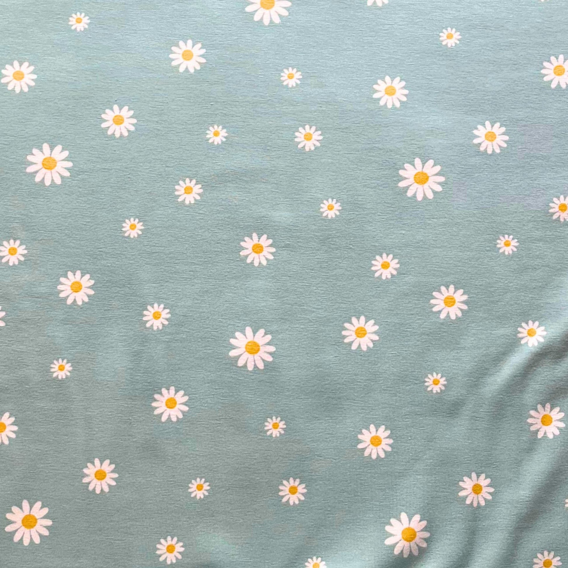 Pattern of white daisies with yellow centers on a blue fabric background