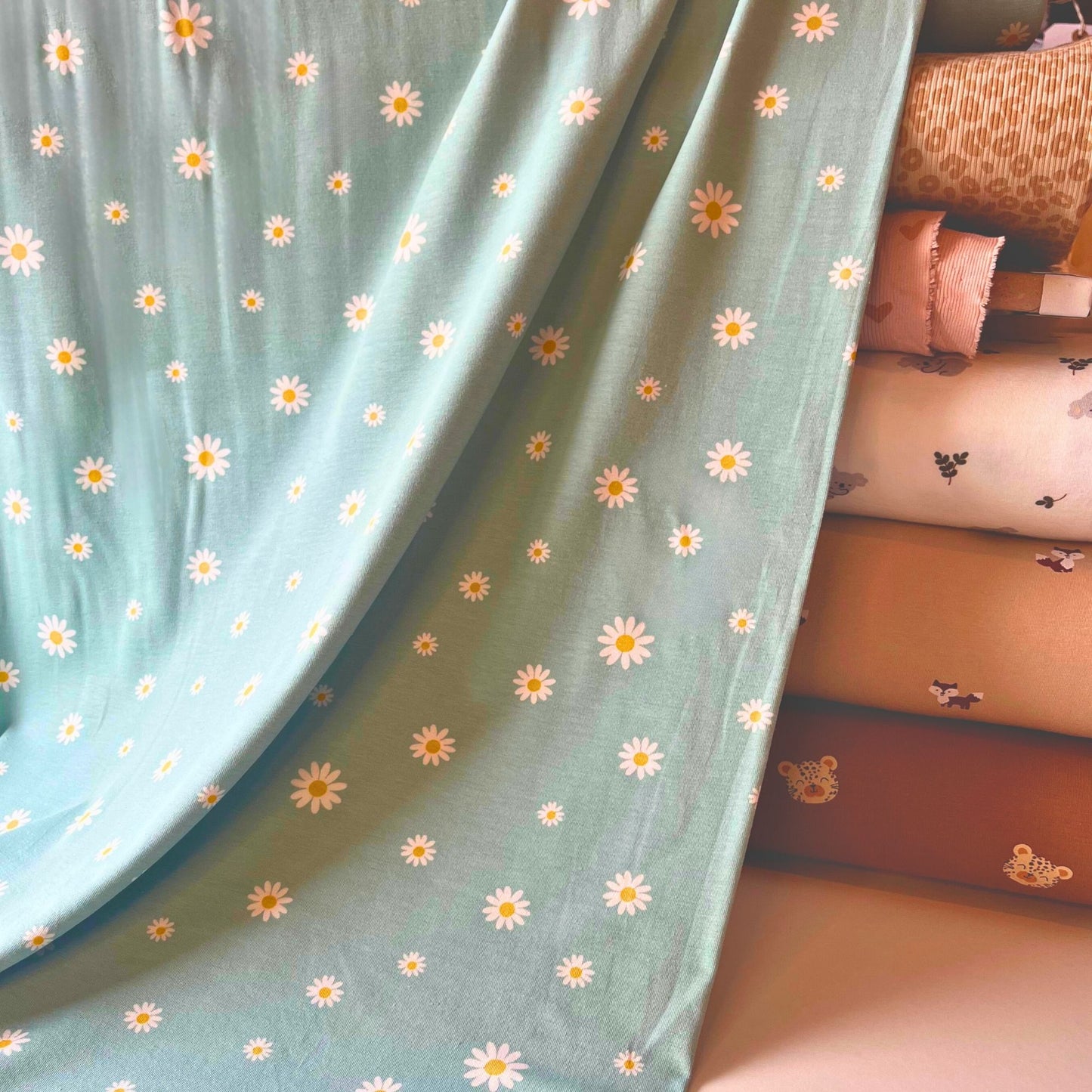 Teal daisy print cotton jersey fabric, ideal for baby and children’s clothes.