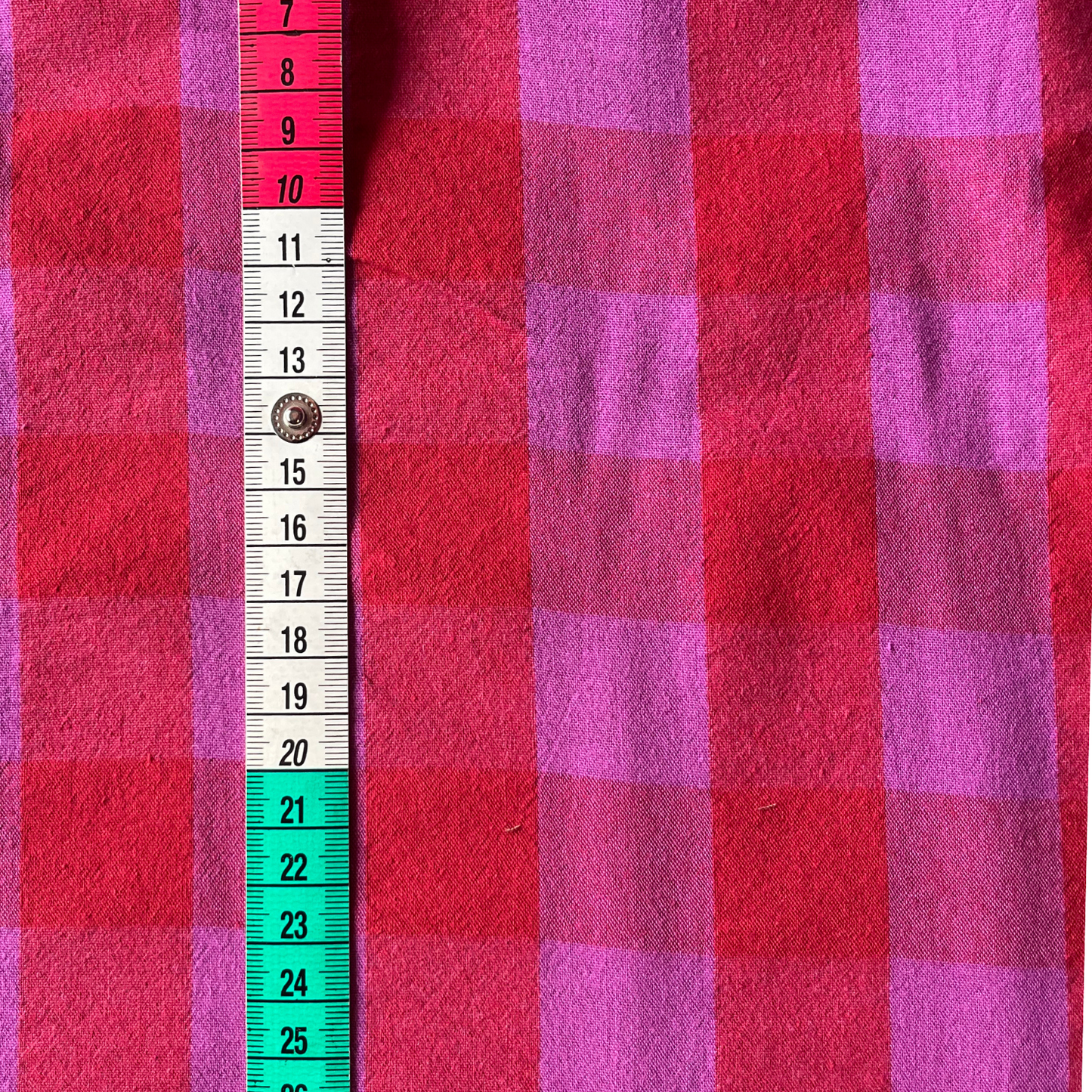 Flat lay of red and hot pink gingham cotton fabric draped to show 135gsm weight and natural drape — 3cm yarn dyed check perfect for handmade party dresses, shirts and barrel leg trousers