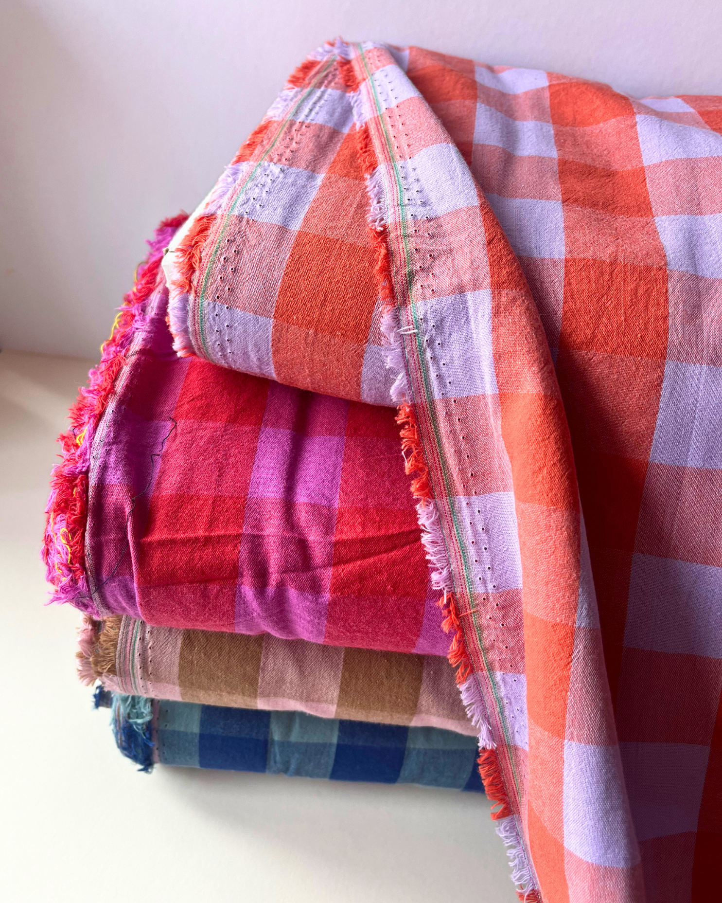 Four colourways of yarn dyed gingham check cotton fabric shown together — pale pink and brown, red and cerise, blue and teal, burnt orange and lavender — 3cm square check, 145cm wide, Oeko-Tex Standard 100 certified woven cotton for women's dressmaking and slow fashion sewing